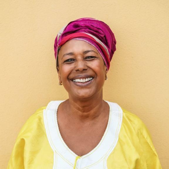 Older black woman smiling on a yellow background